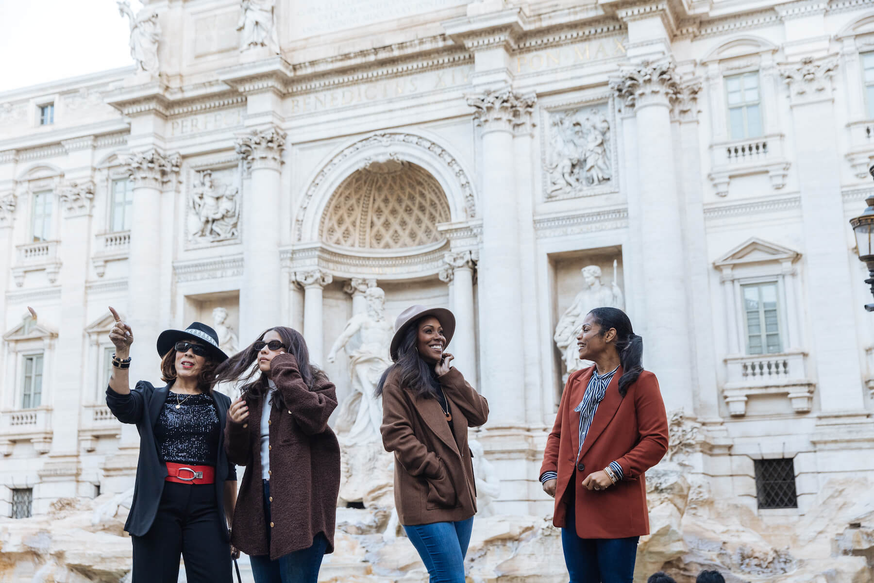 A group of friends talking in front of the Trevi Fountain in Rome on a friend photoshoot with Flytographer
