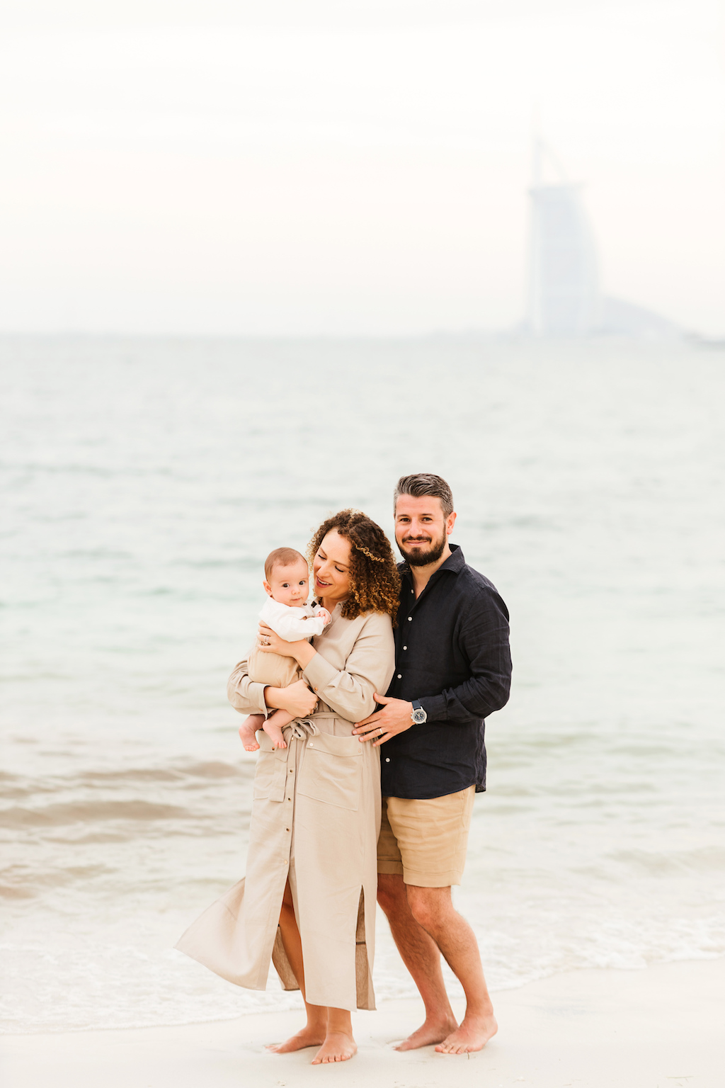 A couple enjoys a happy moment with their baby on the beaches of Dubai on their Flytographer photoshoot.