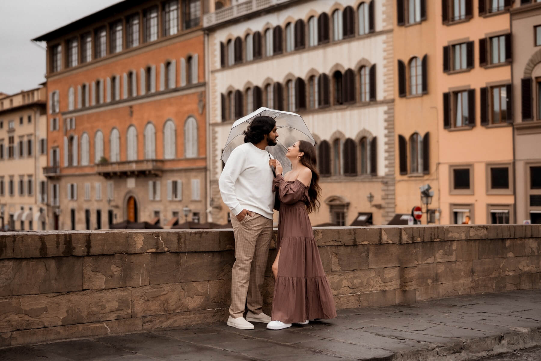 A couple hugging under a clear plastic umbrella on a couple photoshoot with Flytographer in Florence