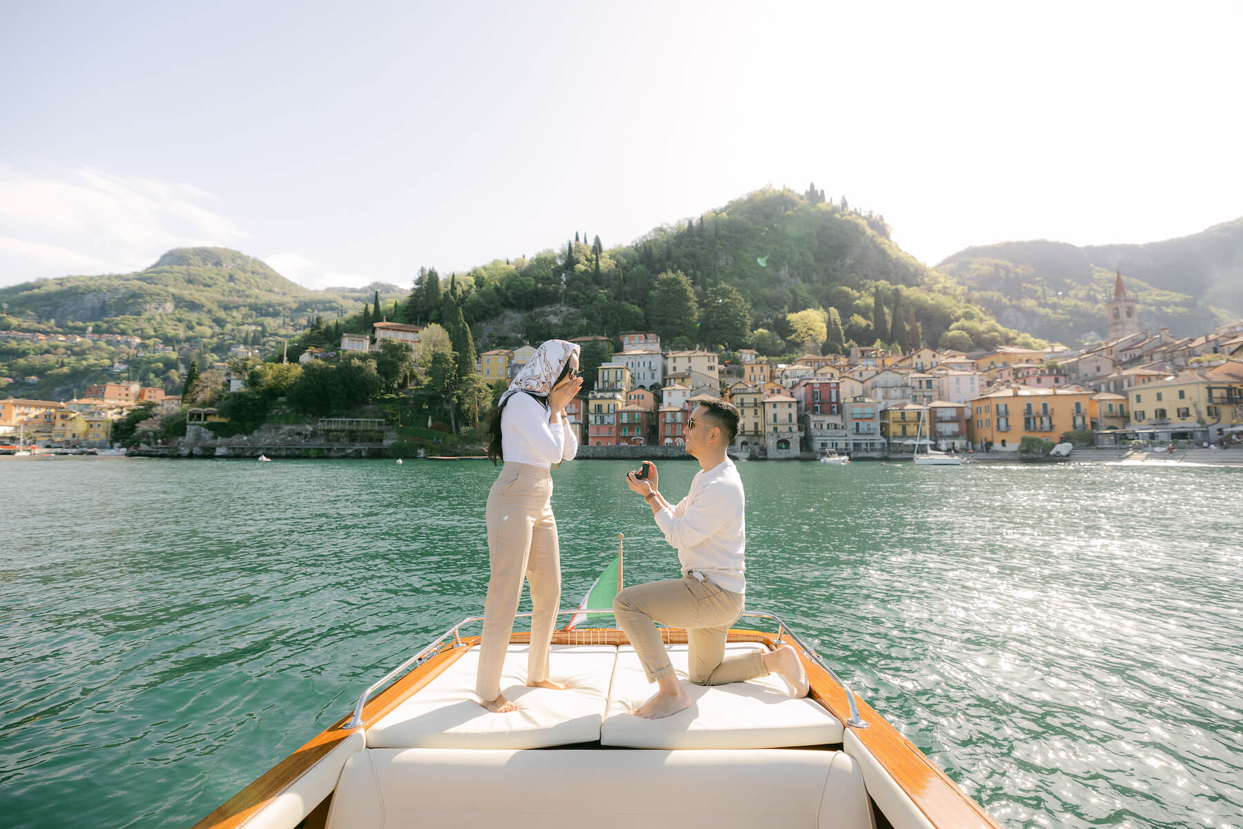 Man on one knee proposing to girlfriend on a speed boat on Lake Como, Italy