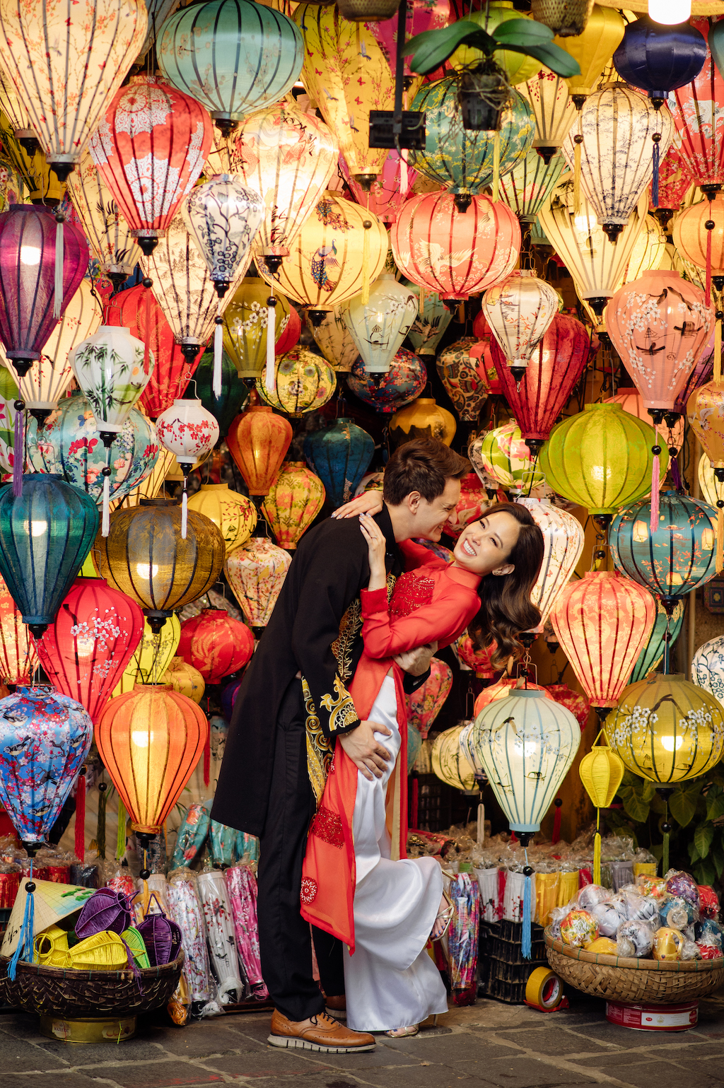 A smiling couple dance in front of colorful lanterns in Hoi An on their Flytographer photoshoot.