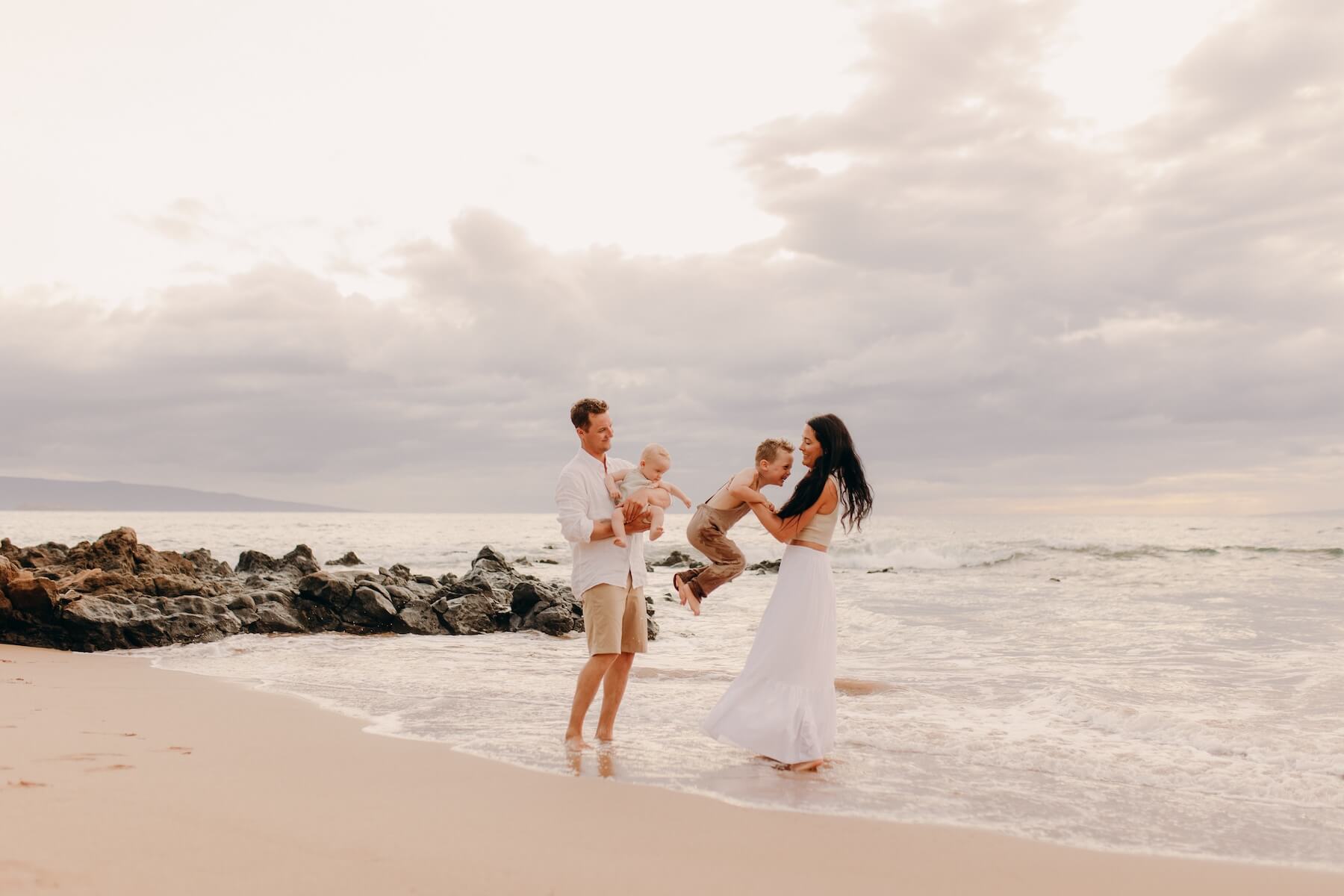A family playing on a beach in Maui on a family photoshoot with Flytographer.