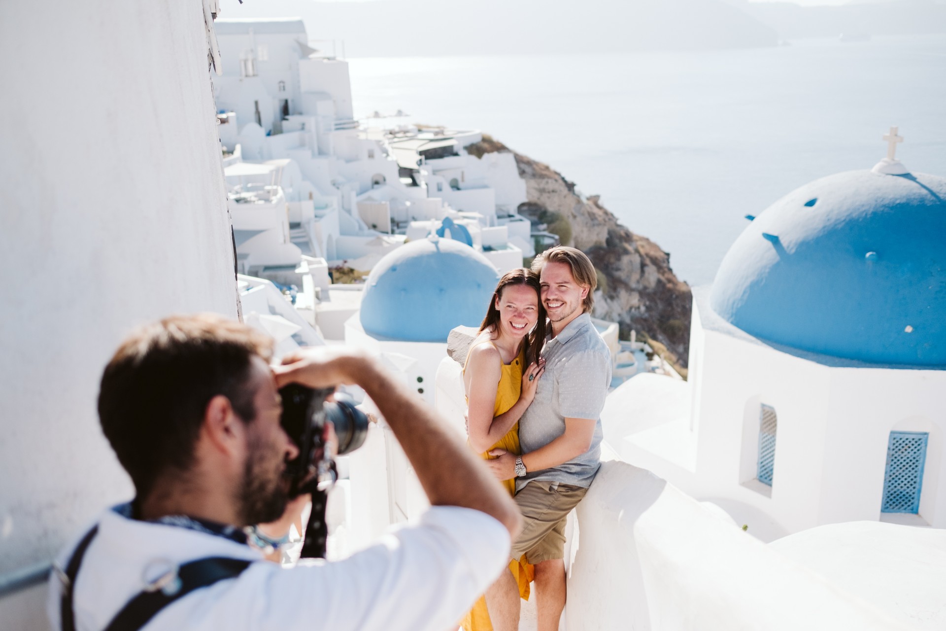 A Flytographer photographer takes a photo of a couple in Santorini during their Flytographer shoot