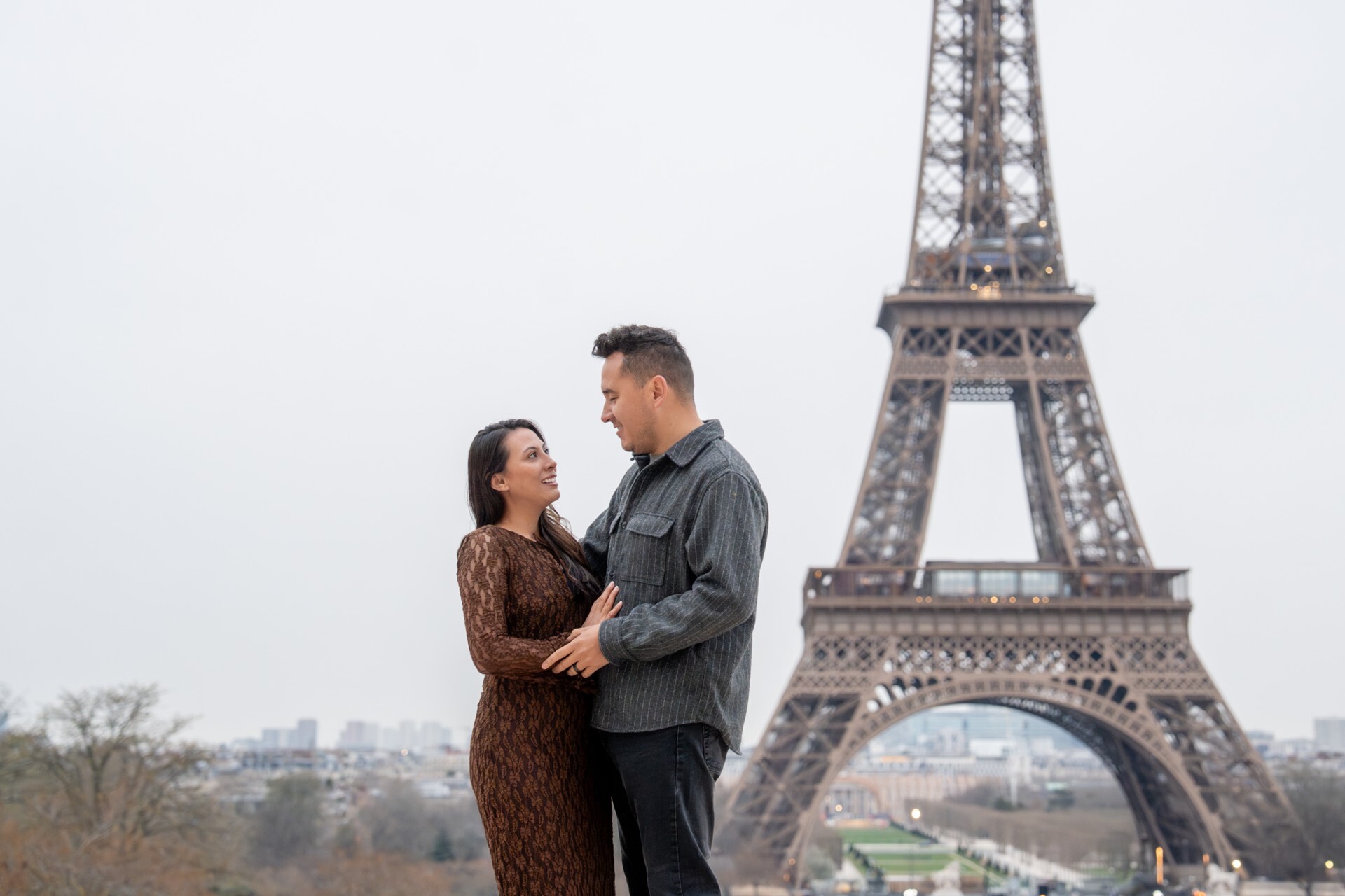 A smiling couple embraces in front of the Eiffel Tower on their Flytographer photo shoot