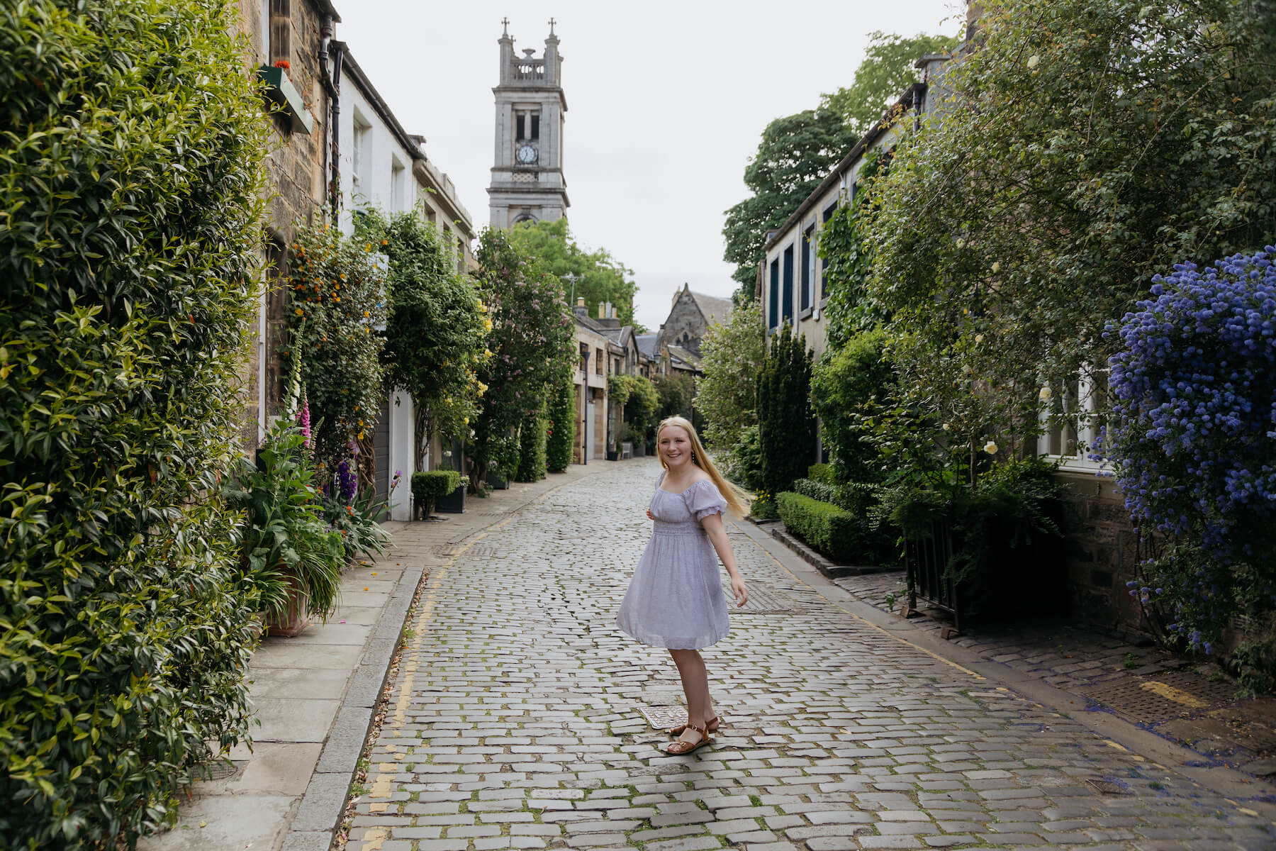 A woman in a purple dress dancing in the streets of Edinburgh on a photoshoot with Flytographer