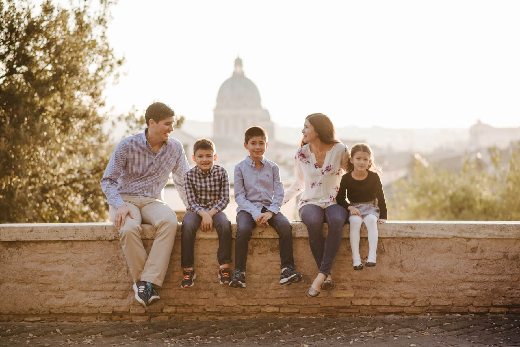 A family sitting on a wall with the Pantheon in the background on a family photoshoot with Flytographer