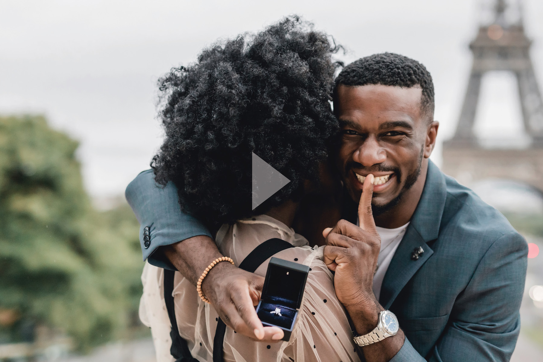 A man smiling with a ring, about to surprise his partner with a proposal