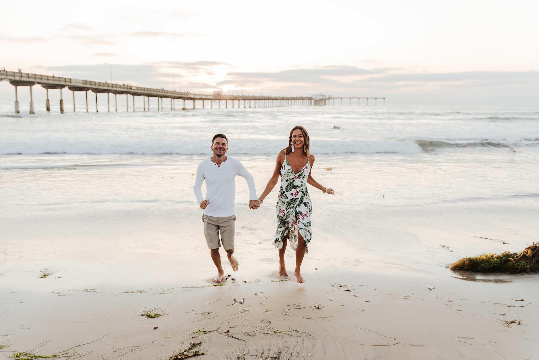 A couple running towards the camera on a couple photoshoot in San Diego with Flytographer