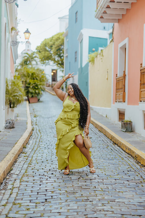 A solo traveler poses in front of a colorful building in San Juan on their Flytographer photoshoot.