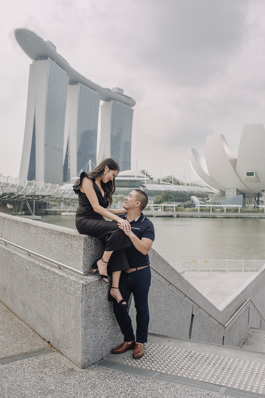 A happy couple smiles at each other in front of the Marina Bay Sands in Singapore on their Flytographer photoshoot.