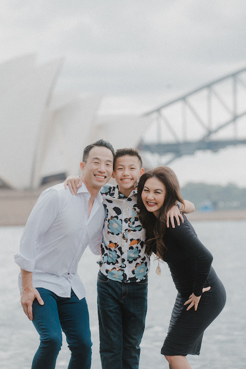 A smiling family poses in front of the Sydney Opera House on their Flytographer photoshoot.