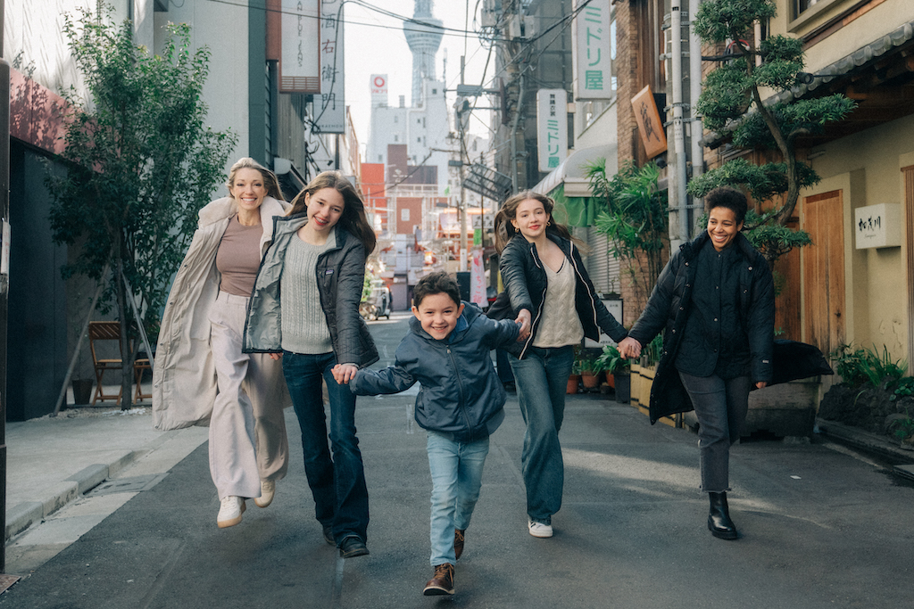 A happy family hold hands and run towards the camera in Tokyo on their Flytographer photoshoot.